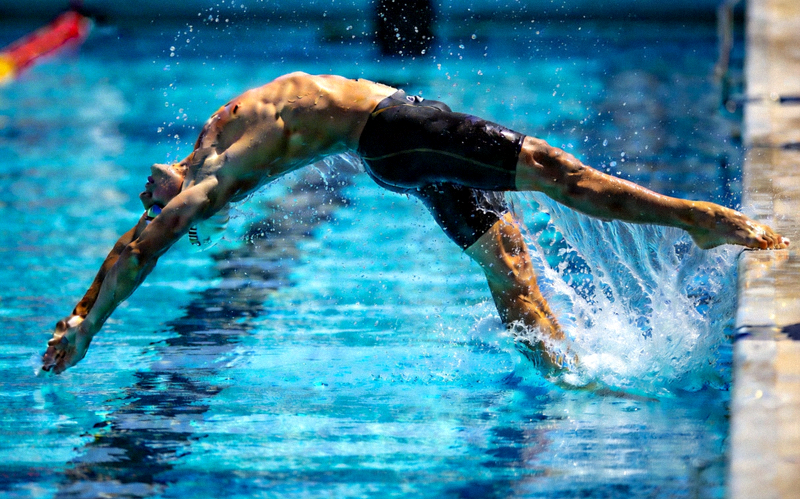 游泳运动员在泳池中转身瞬间，水花四溅，动作流畅